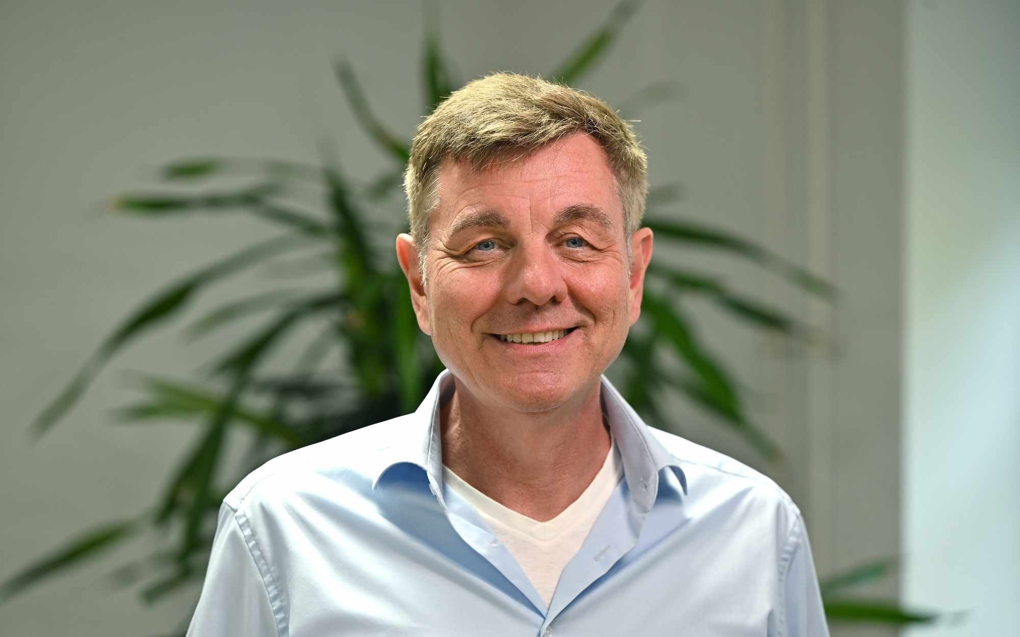 Mediaberater Michael Wicker steht vor einem neutralen Hintergrund und lächelt in die Kamera